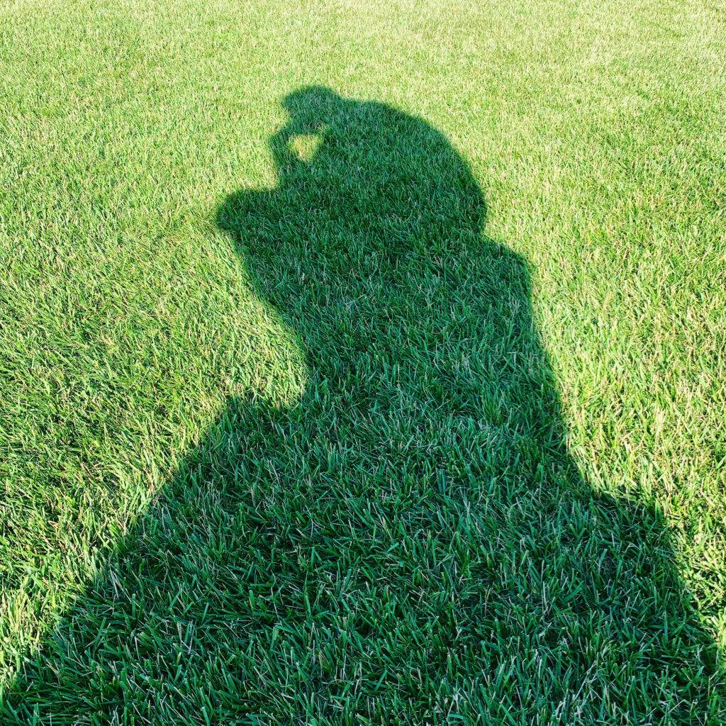 Shadow on green grass of August Rodin's "The Thinker" sculpture at the Nelson-Atkins Museum of Art. 